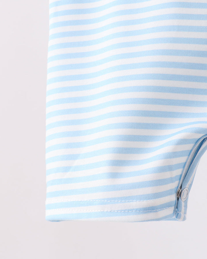 Close-up of a light blue and white striped garment, showing the fabric texture and a snap button closure on the bottom corner.