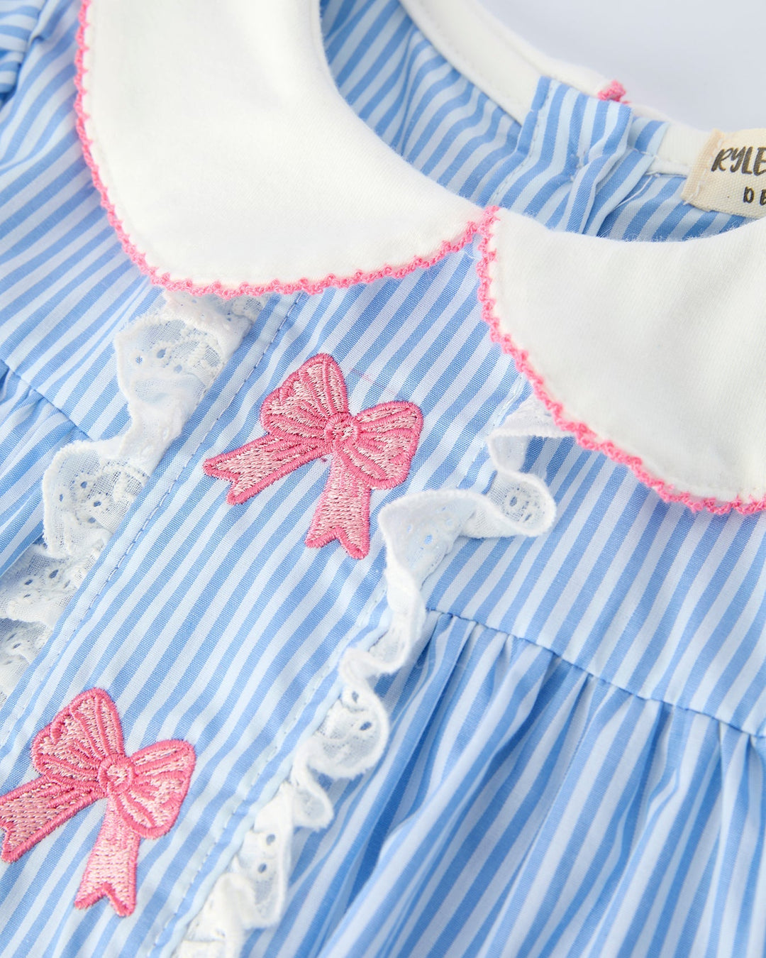 Blue and white striped dress with pink bows and white lace details on a white background