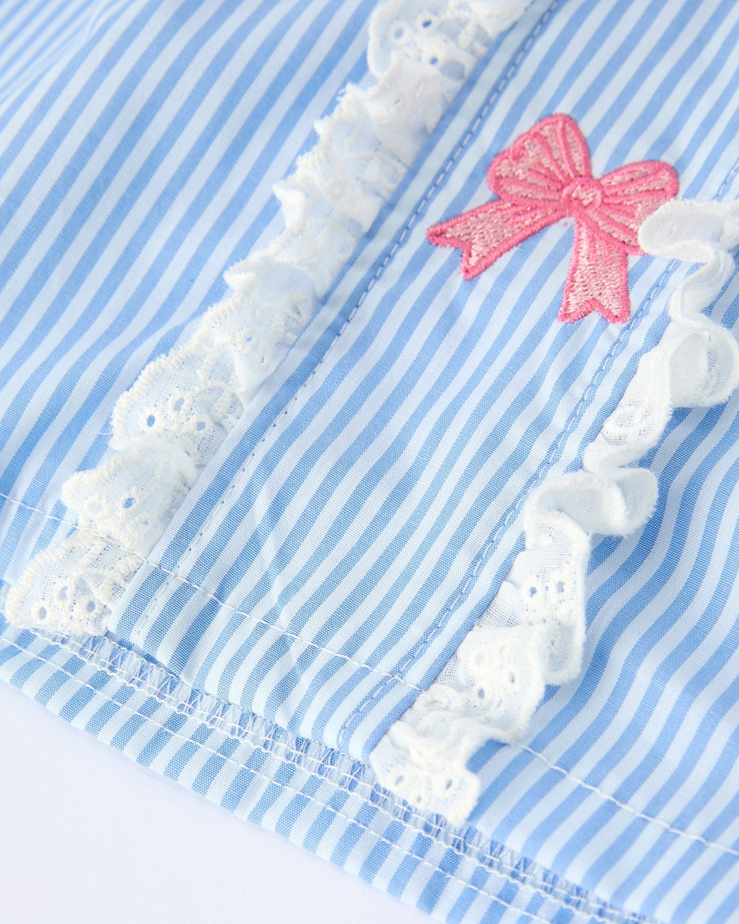 Blue and white striped fabric with white lace trim and a pink bow on a white background