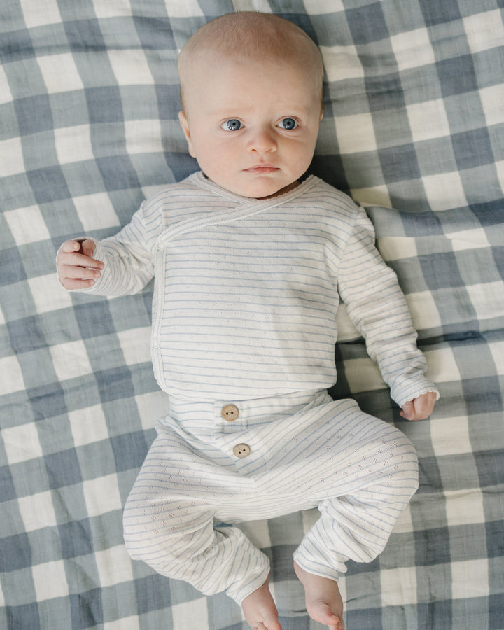 Baby in a striped outfit lying on a checkered blanket