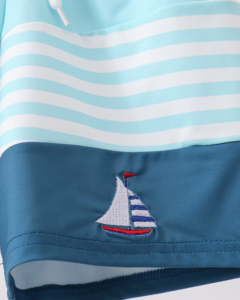 Blue and white striped fabric with a sailboat design on a white background
