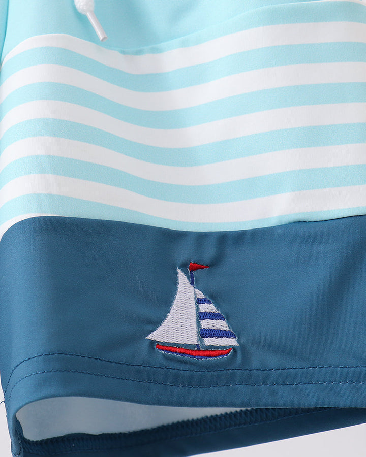 Blue and white striped fabric with a sailboat design on a white background