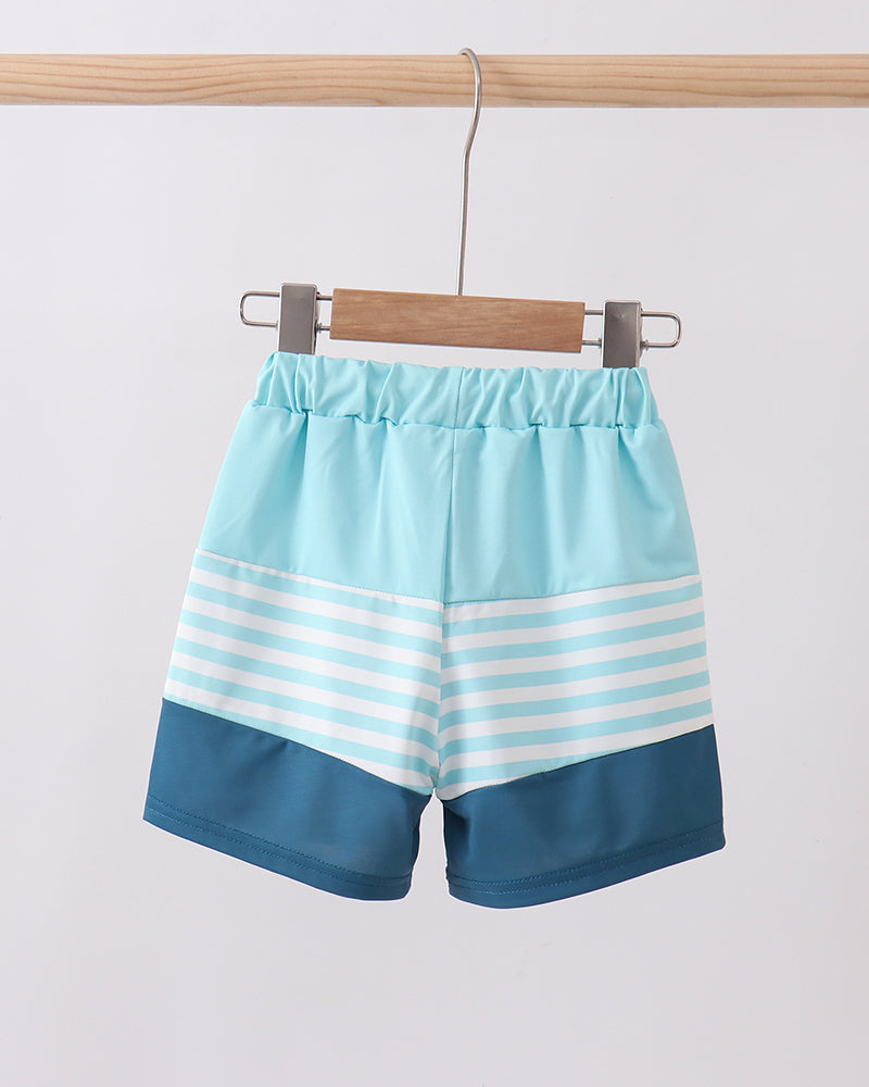 Blue and white striped shorts hanging on a wooden hanger against a light gray background