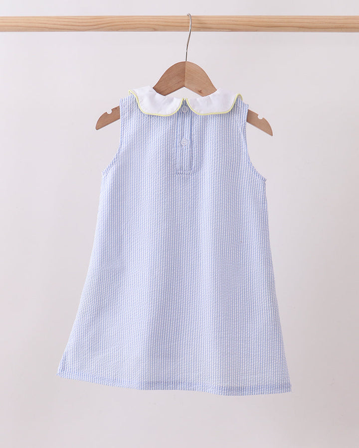Blue striped dress with white collar on a wooden hanger against a light background