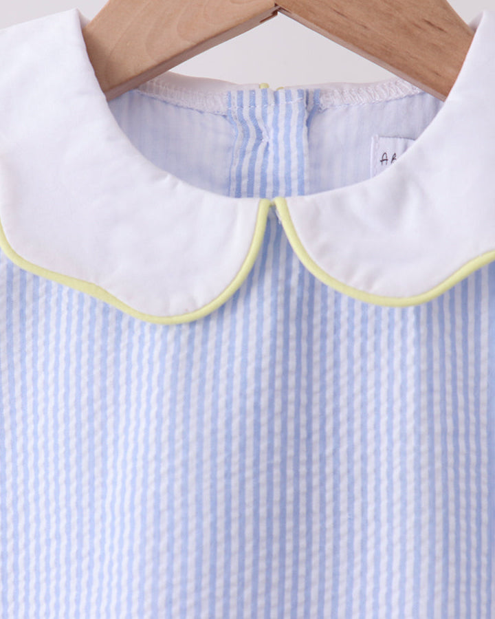 Close-up of a blue and white striped shirt with a white collar on a wooden hanger.