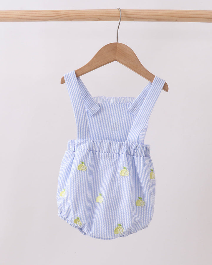 Blue and white striped romper with pineapple patterns on a wooden hanger against a light background