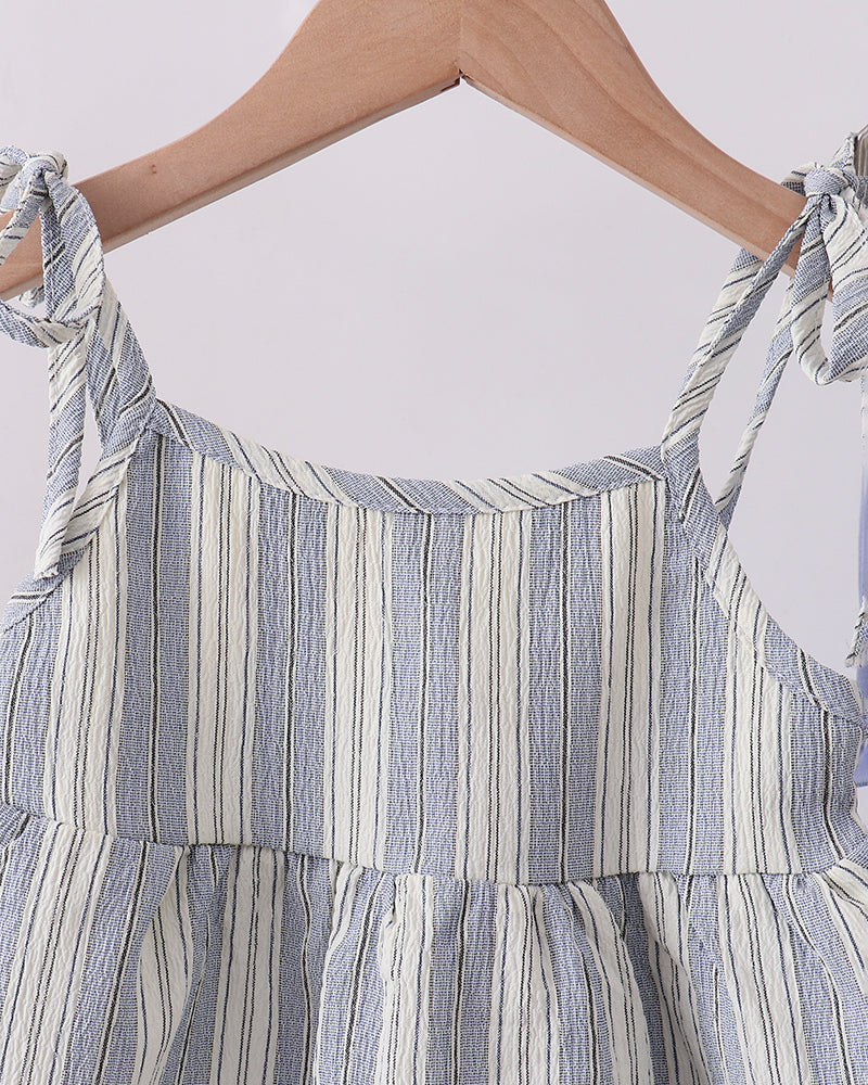 Close-up of a blue and white striped dress with tied straps on a white background