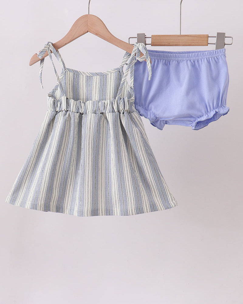 Striped dress and purple bloomers hanging on a rack against a light background