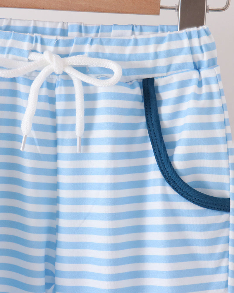 Light blue and white striped shorts with a white drawstring and a dark blue pocket, hanging on a wooden hanger.