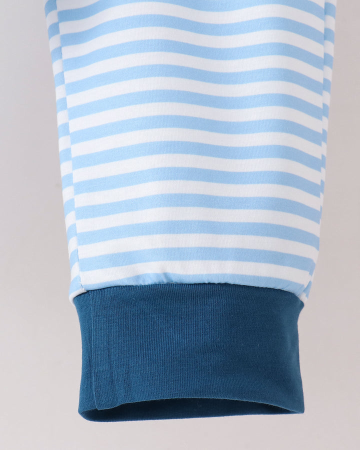 Close-up of a light blue and white striped sleeve with a solid dark blue ribbed cuff, shown against a light gray background.