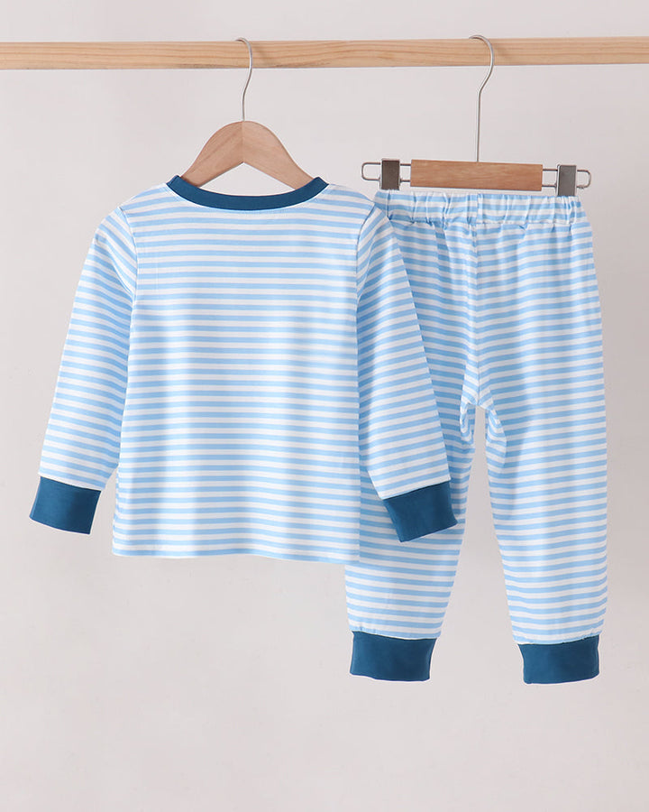 A two-piece baby pajama set consisting of a long-sleeve top and matching pants, hanging on wooden hangers from a light wood rod. The pajamas feature a light blue and white horizontal stripe pattern with solid dark blue ribbed trim on the collar, cuffs, and hems.