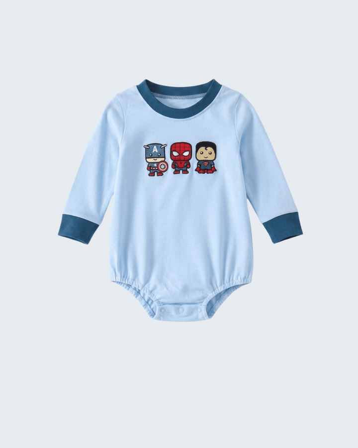 A light blue long-sleeve baby bodysuit with dark blue ribbed collar and cuffs, featuring three cartoon superhero characters printed on the chest.