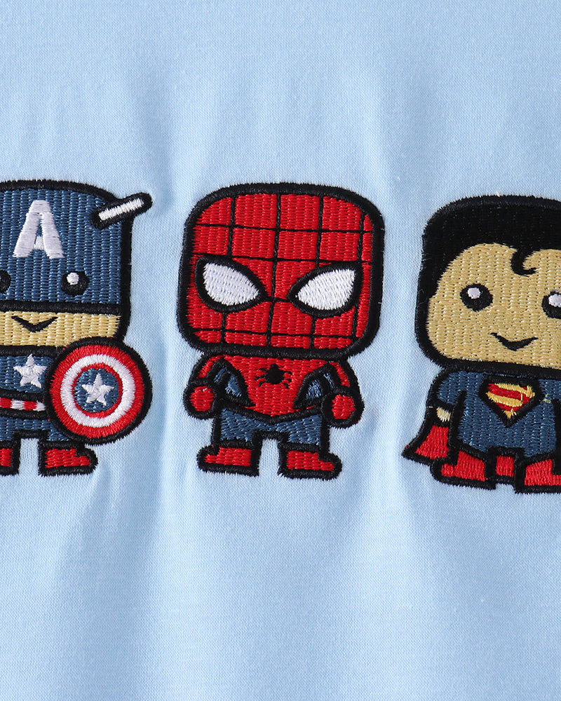 Close-up of a light blue fabric garment featuring three embroidered cartoon superhero patches: Captain America on the left, Spider-Man in the center, and Superman on the right.