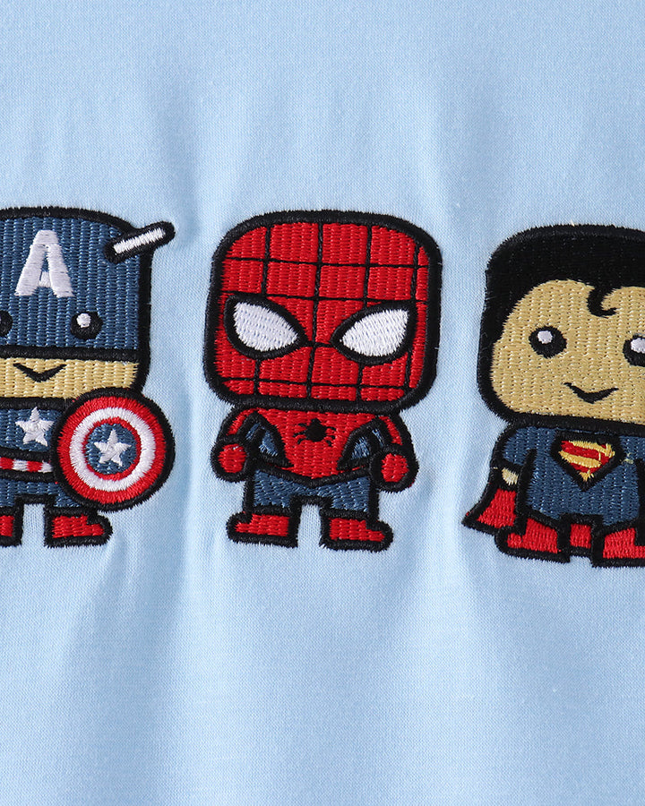 Close-up of a light blue fabric garment featuring three embroidered cartoon superhero patches: Captain America on the left, Spider-Man in the center, and Superman on the right.