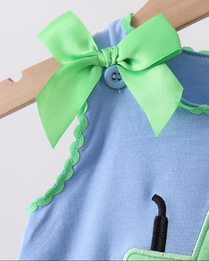 Blue dress with a green bow and button detail on a light gray background