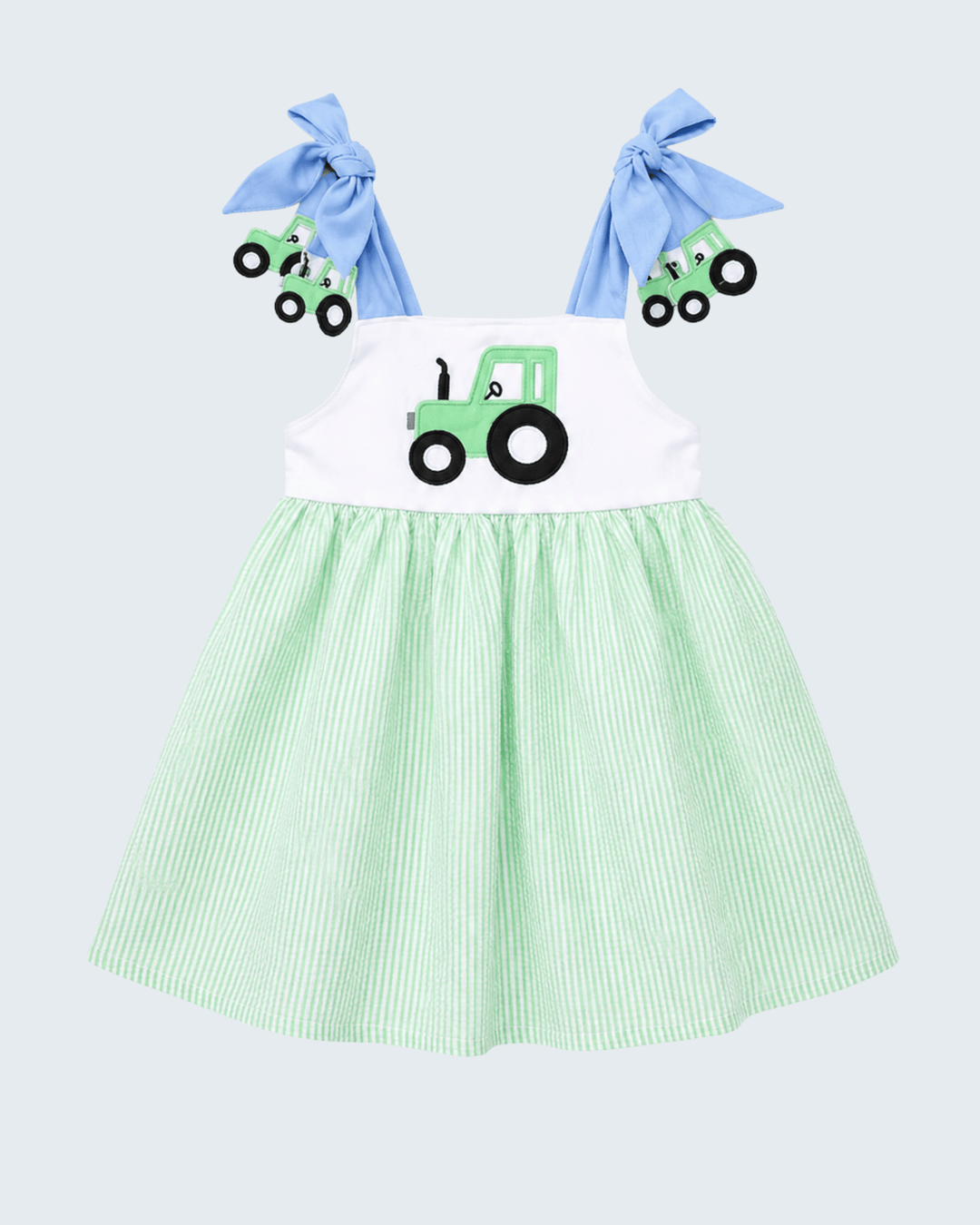 Green and white dress with tractor design and blue hair bows on a light gray background