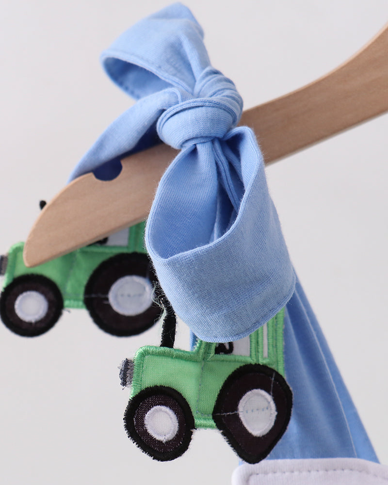 Baby bib with blue bow and green tractor design on a white background