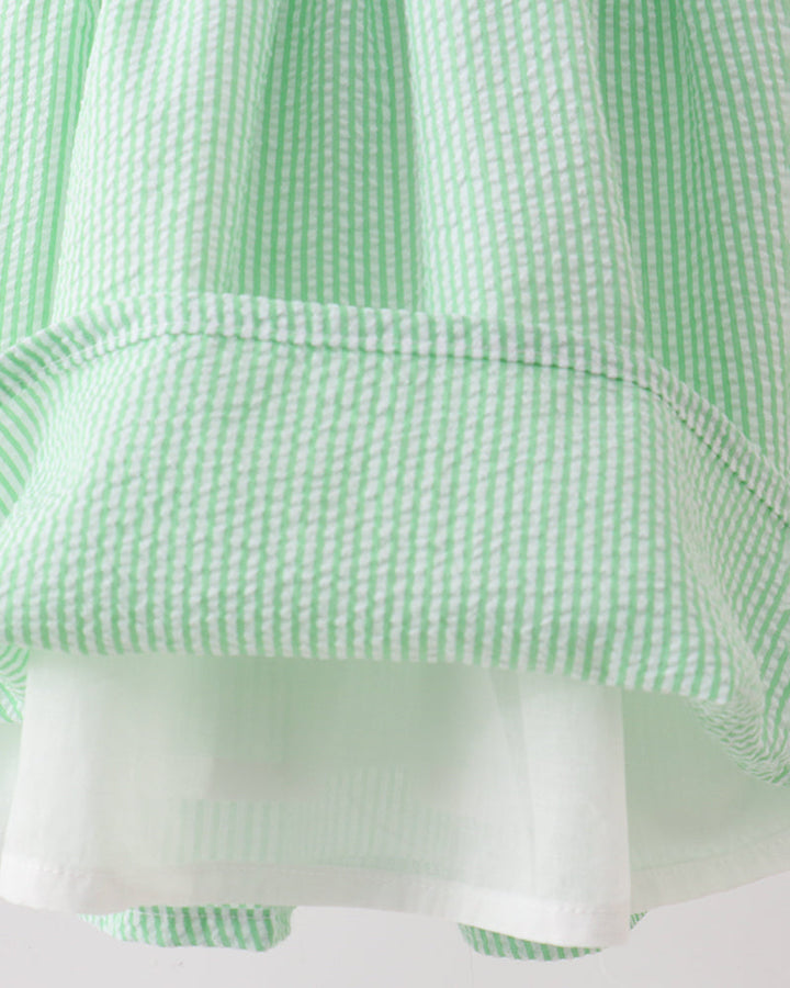 Close-up of a green and white checkered fabric with a pocket detail.
