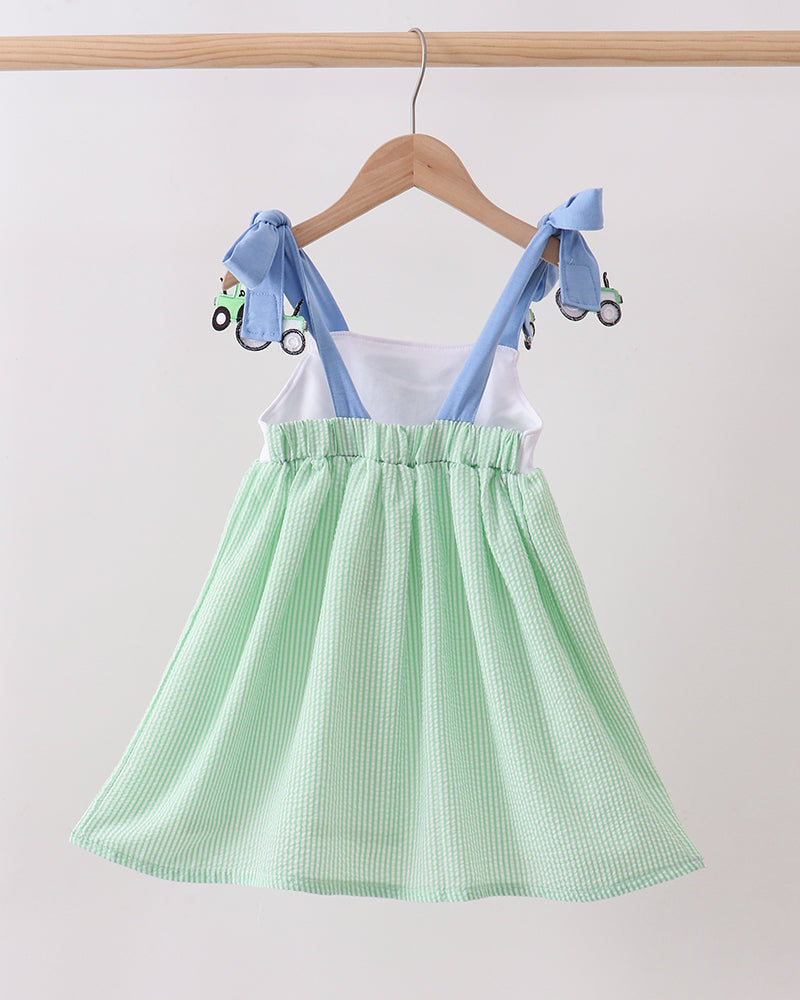 Green checkered dress with blue straps on a hanger against a white background
