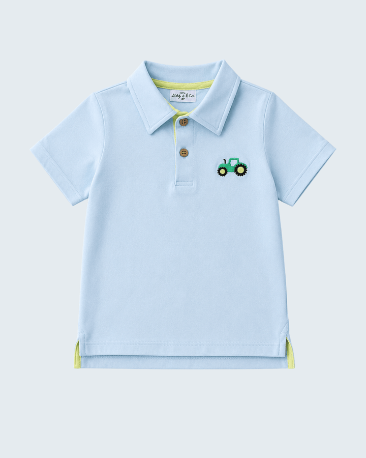A light blue short-sleeve polo shirt for toddlers, featuring a small embroidered green tractor on the left chest, a two-button placket, and subtle lime green trim details.
