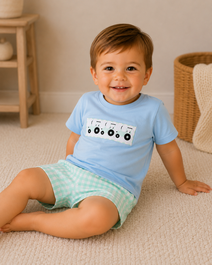 Child wearing a light blue shirt with a graphic design sitting on a carpeted floor.