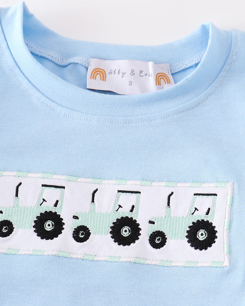 Light blue shirt with a decorative band featuring black tractors on a white background.