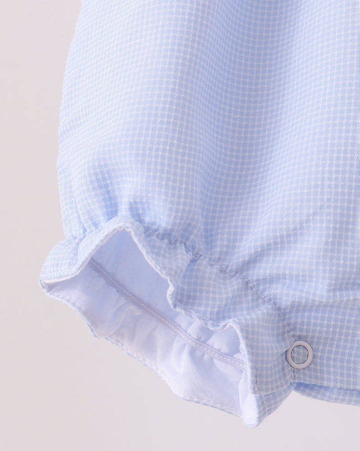 Light blue checkered romper with ruffled leg cuffs and snap detail