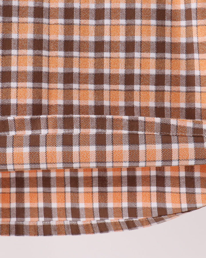 Orange and brown plaid fabric panel with white grid lines on dress