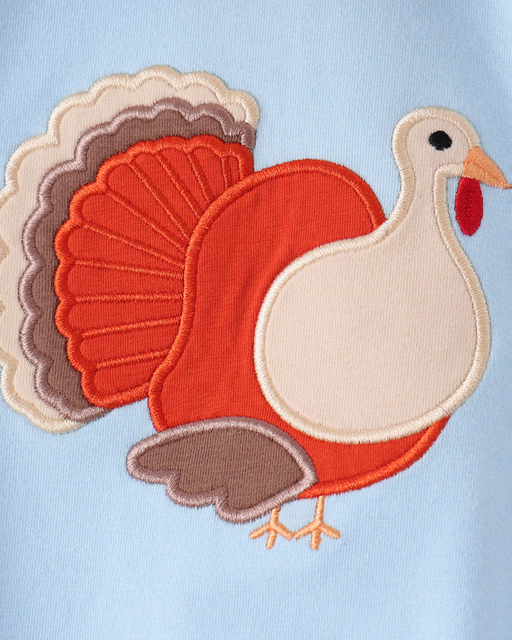Light blue romper close-up of embroidered turkey and layered applique accents