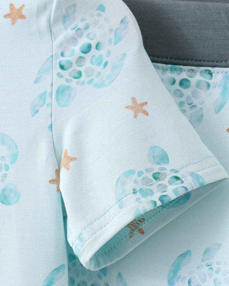 Baby outfit with sea-themed print on a light blue background