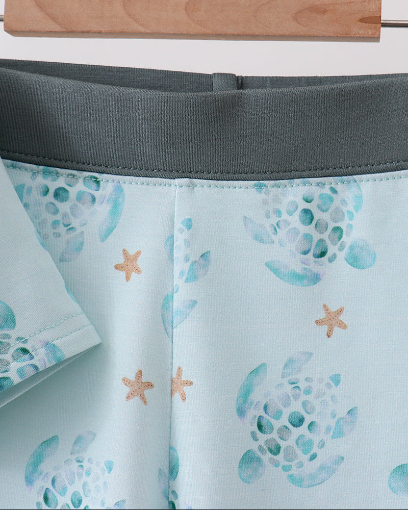 Shorts with starfish and shell pattern on a hanger against a white background