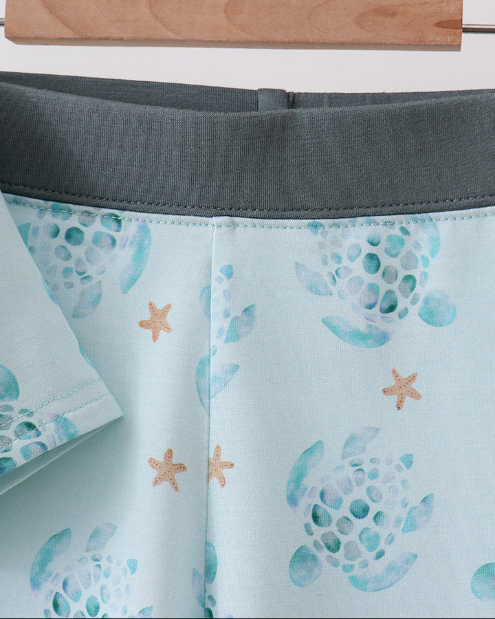 Shorts with starfish and shell pattern on a hanger against a white background