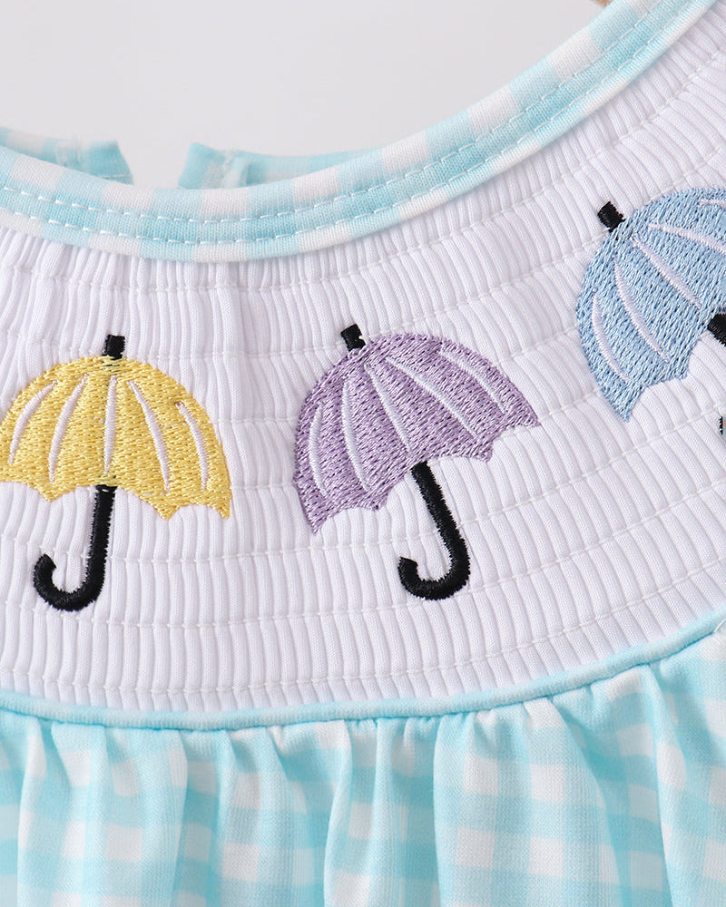 Close-up of a dress with embroidered umbrellas on a checkered pattern