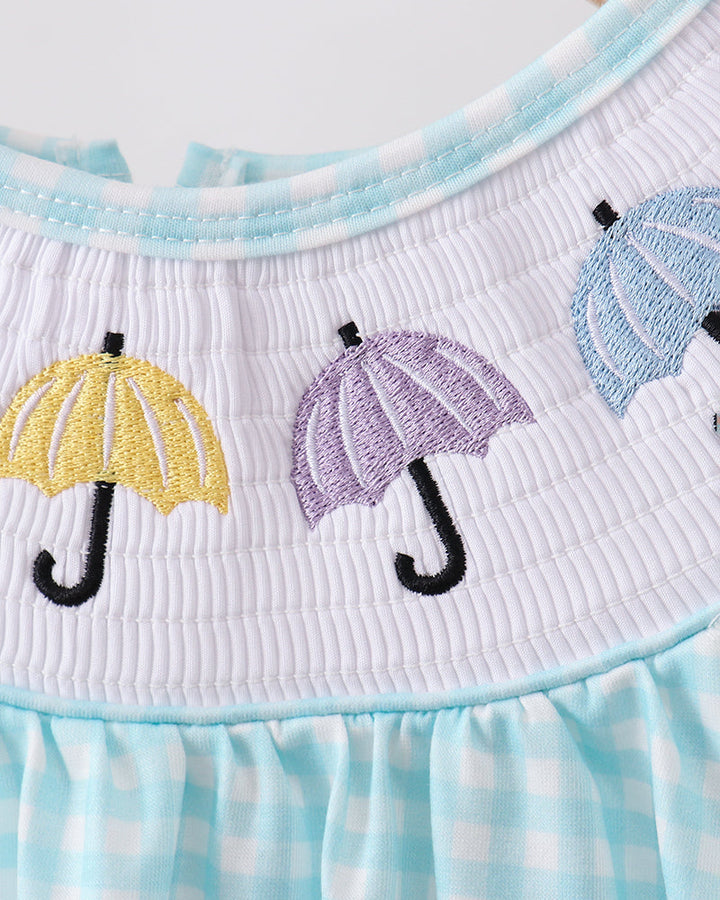 Close-up of a dress with embroidered umbrellas on a checkered pattern