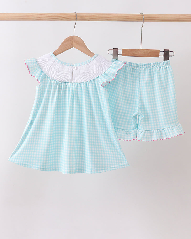Light blue checkered top and shorts set hanging on a wooden hanger against a white background