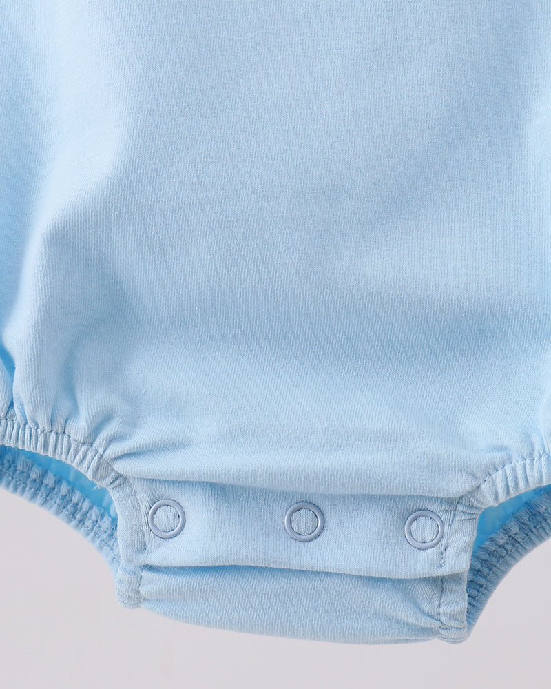Close-up of a baby bodysuit in light blue, showing the snap-button crotch closure with three silver snaps on a light gray background.