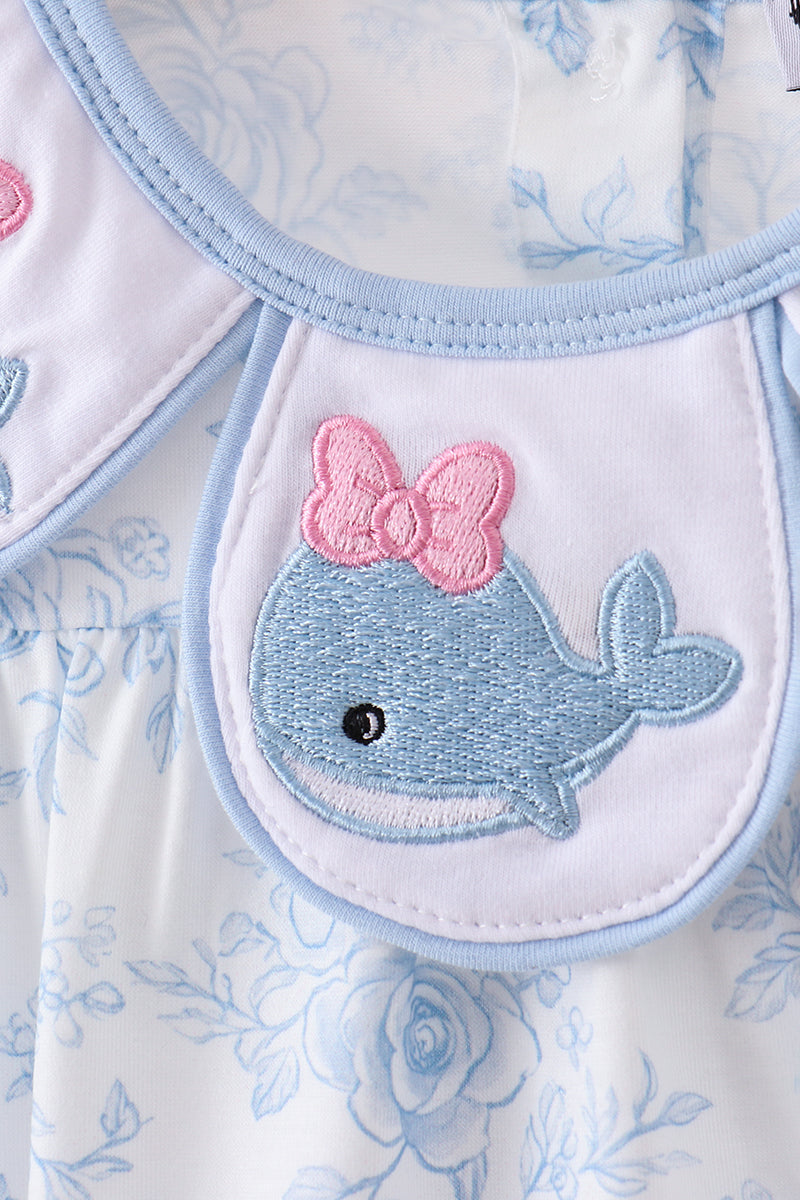 Embroidered whale with a pink bow on a floral patterned fabric