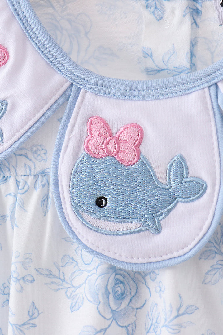 Embroidered whale with a pink bow on a floral patterned fabric