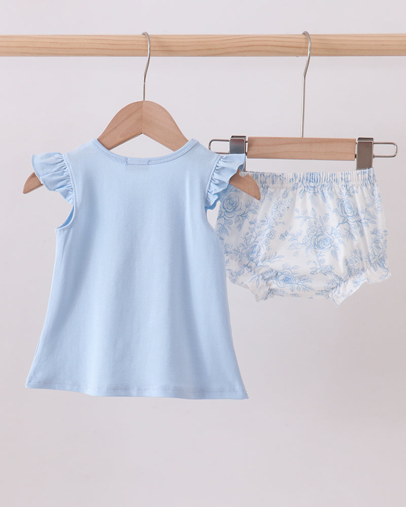 Light blue sleeveless top and floral outfit on a wooden hanger against a light gray background