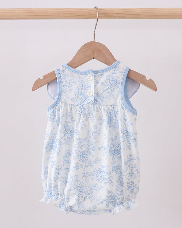 Baby romper with blue floral pattern hanging on a wooden hanger against a white background