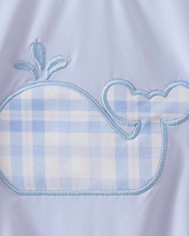 Embroidered whale design on a light blue fabric background