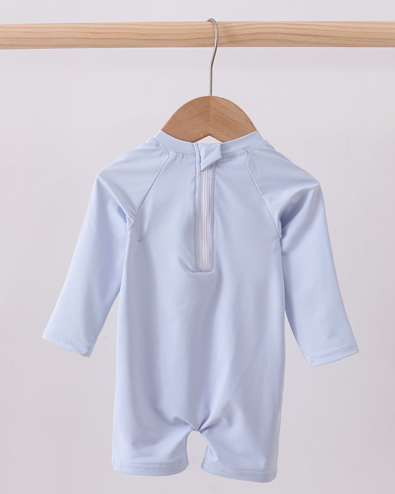 Light blue swimsuit on a wooden hanger against a light gray background