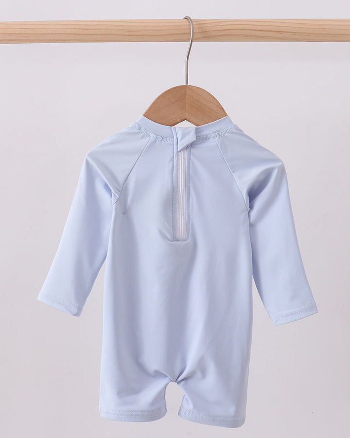 Light blue swimsuit on a wooden hanger against a light gray background