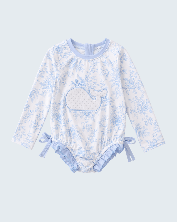 Baby rashguard with whale design on a light blue background