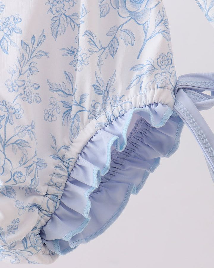 Floral patterned baby romper with ruffled details on a light background