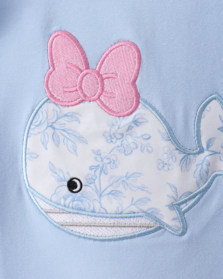 Embroidered whale with a pink bow on a light blue background