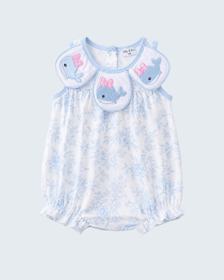 Baby romper with whale and bow design on a light blue background