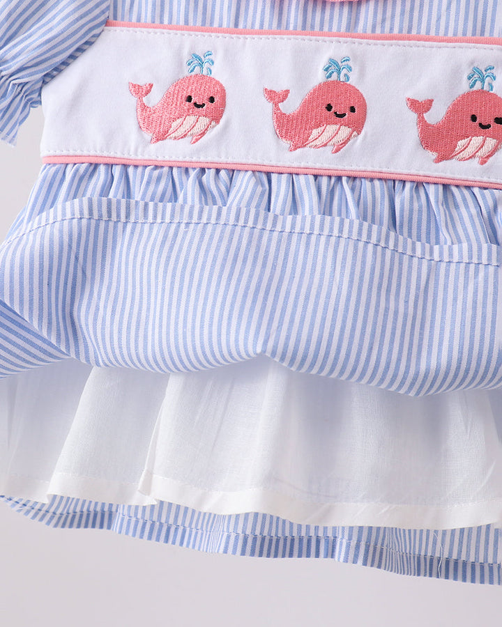 Close-up of a dress with pink whales on a white background