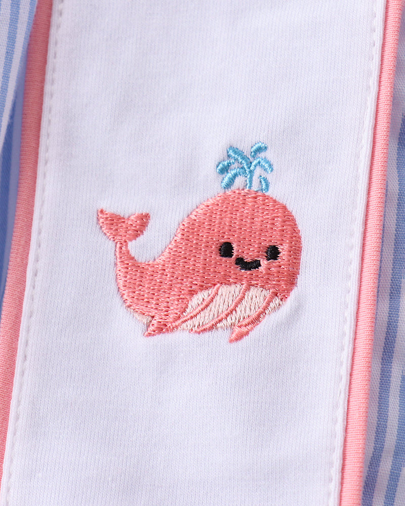 Embroidered pink whale design on a white background with pink and blue borders.