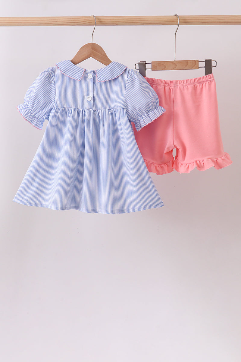 Light blue dress with puffed sleeves and pink shorts on hangers against a light background